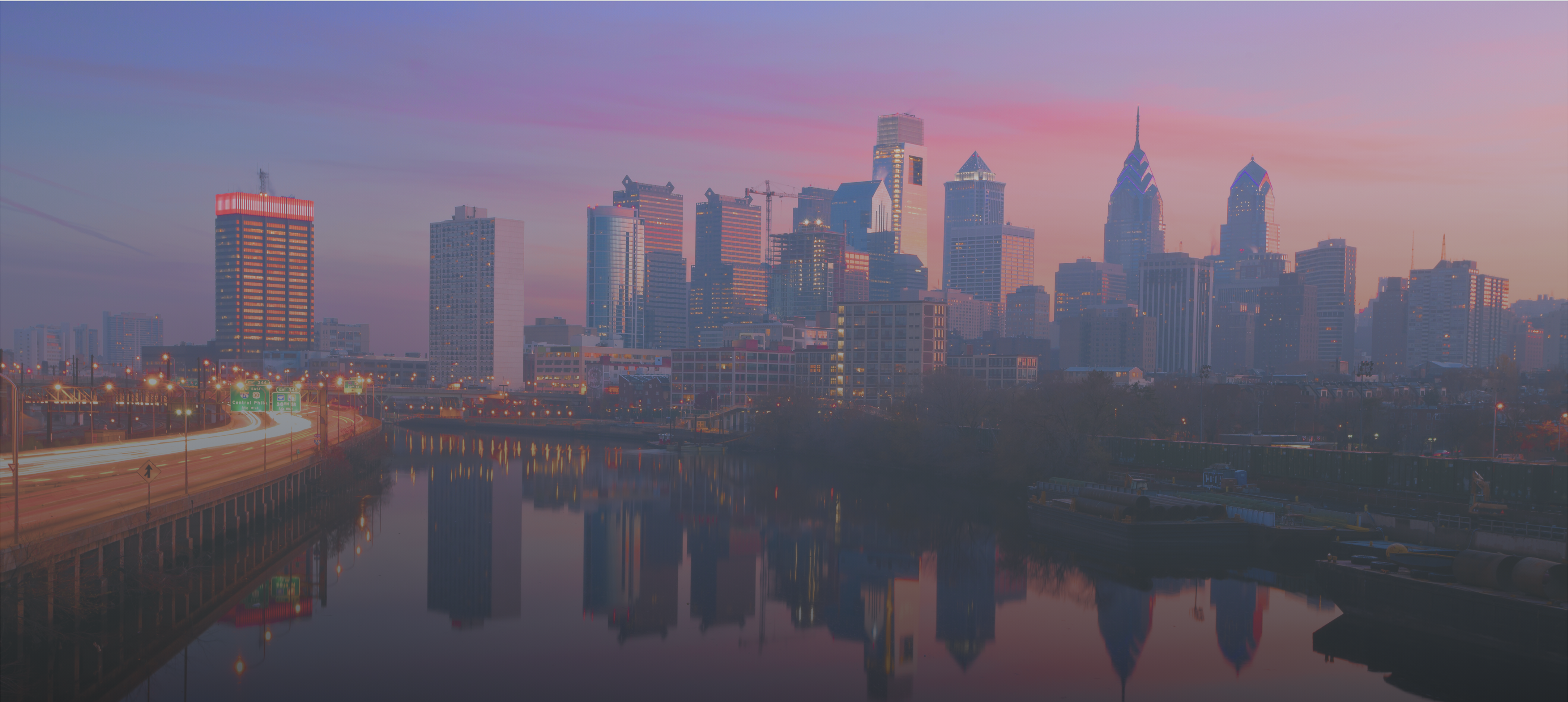 a background image of the Philadelphia skyline and, in closer in frame, a park with a wide river running through it. the skyline is reflected in the water.